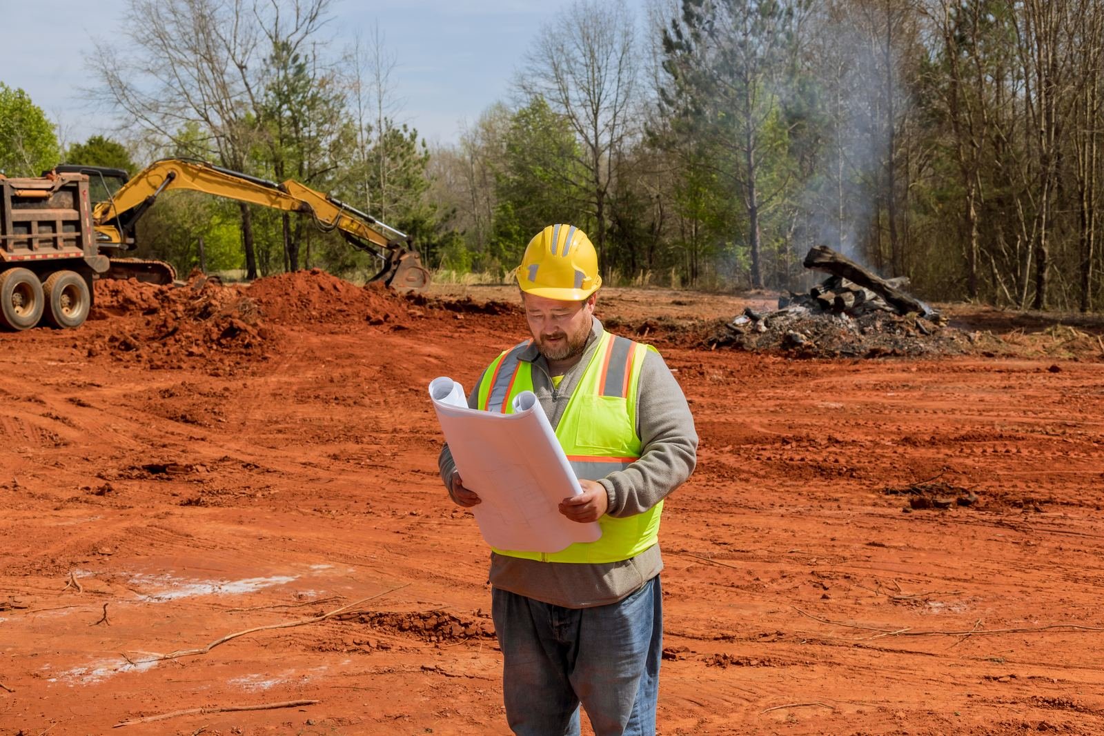 Engineer reviewing development plans on a cleared parcel